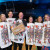 Six Quiz Night guests in letter-c-themed fancy dress as playing cards, holding the prize for winning table
