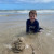 A student sitting in the shallows, enjoying a Vacation Care excursion to the beach