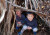 Two students smiling while looking out from inside a structure made out of fallen sticks on ELC Bush Day