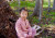 A student sitting next to a large pile of leaves on ELC Bush Day