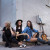 Germein Sisters sitting on a corner footpath holding musical instruments