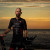 Troy Harrison standing with his bicycle, with the ocean in the background